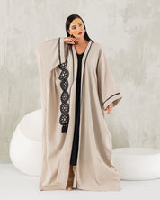 Beige linen abaya with black trims.